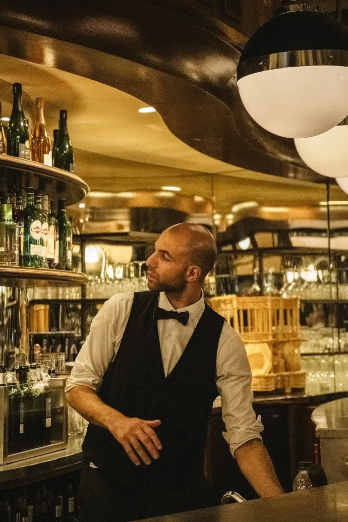 a man wearing a bow tie standing in front of a bar